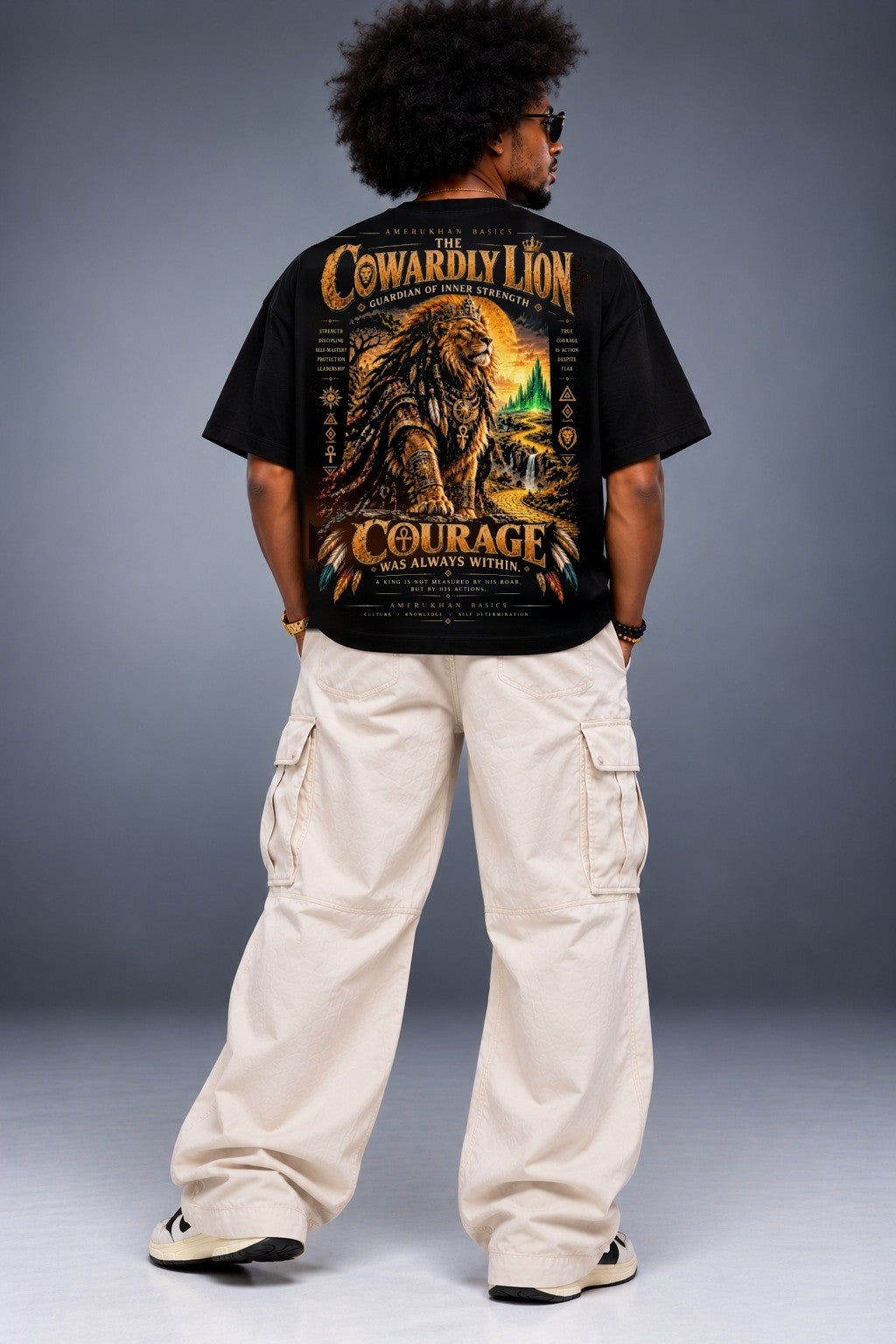 Model wearing the Cowardly Lion Black heritage Wizard of Oz graphic tee, back view with oversized black tee and cream cargo pants