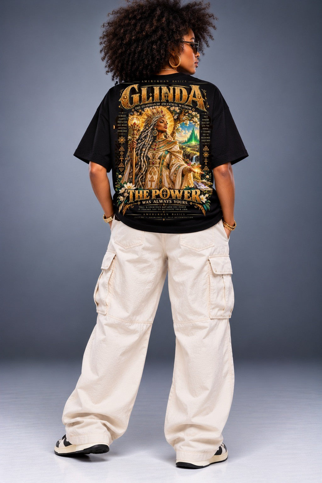 Model wearing the Glinda Black heritage Wizard of Oz graphic tee, back view with oversized black tee and cream cargo pants