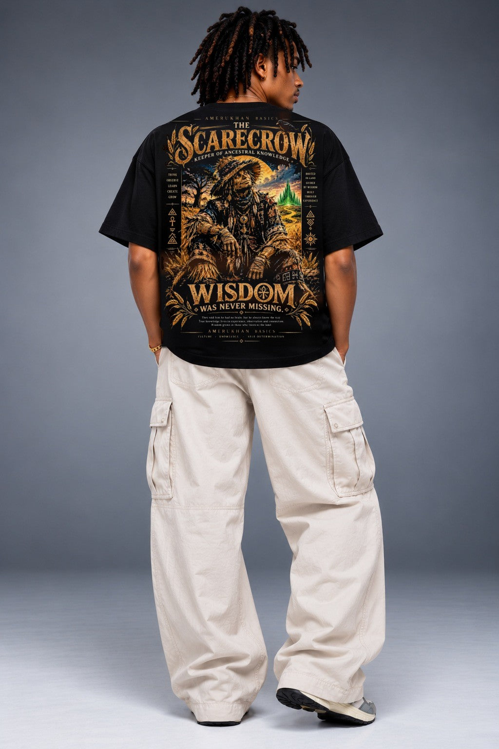 Model wearing the Scarecrow Black heritage Wizard of Oz graphic tee, back view with oversized black tee and cream cargo pants