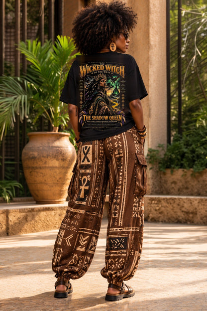 Model wearing the Shadow Queen Wicked Witch Black heritage Wizard of Oz graphic tee, back view with mudcloth print pants